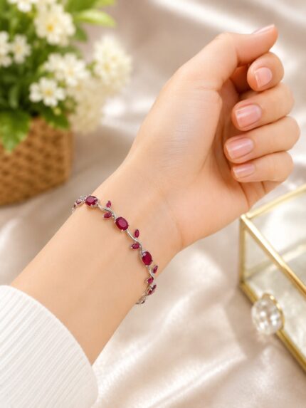 Elegant silver-finish vine bracelet with ruby red stones and leaf detailing for a classy modern look.