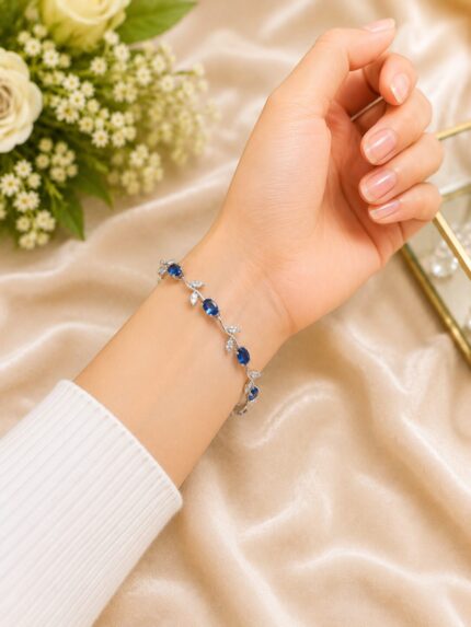 Elegant silver-finish bracelet with sapphire blue stones and crystal leaf detailing for a graceful luxury look